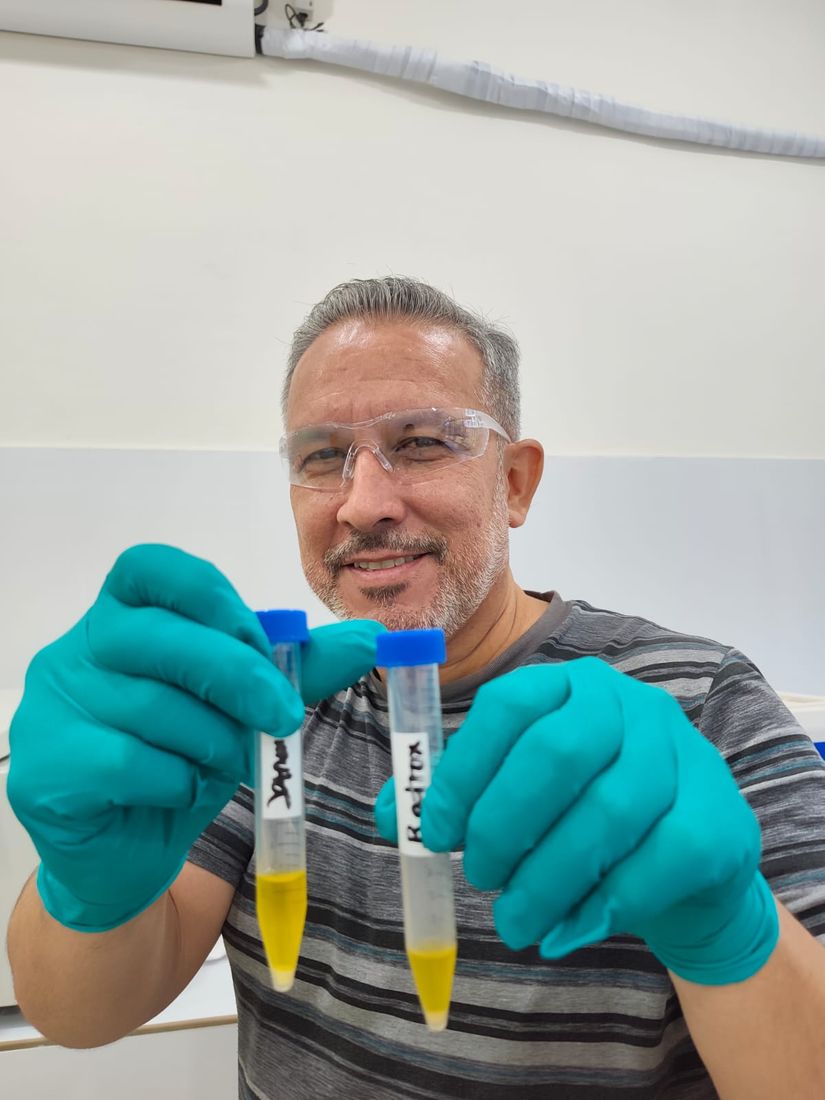 Técnico con lentes de seguridad y guantes de nitrilo sostiene dos tubos rotulados con veneno recién extraído.
